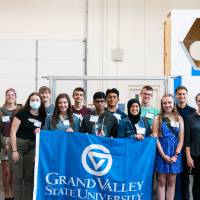 Students pose with the GVSU flag